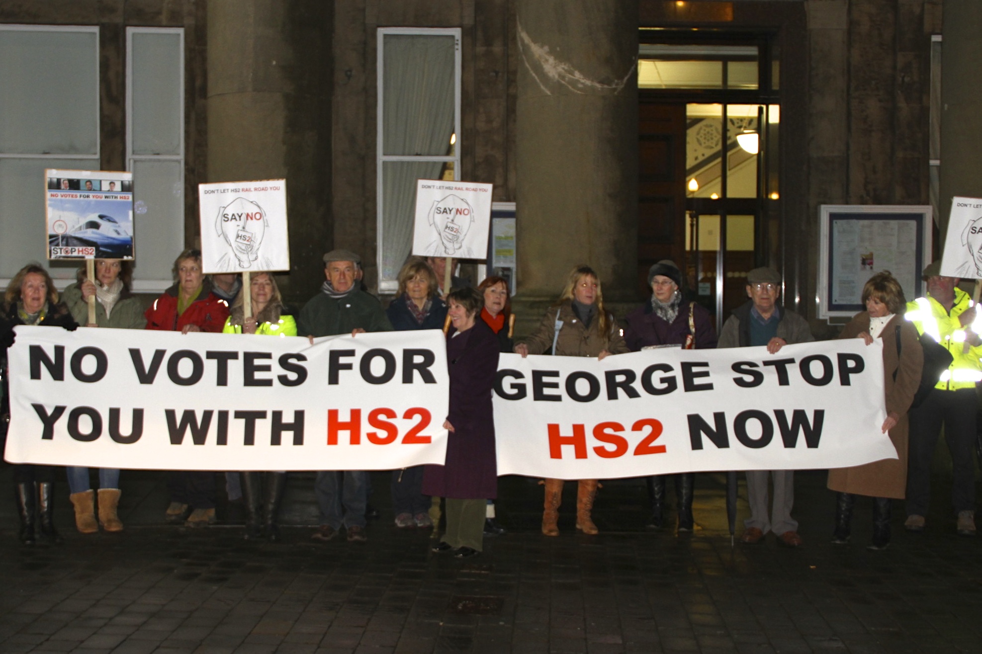 Protest outside George Osborne's meeting with Parish Councillors: signs read "no votes for you with HS2" and "George Stop HS2 now"